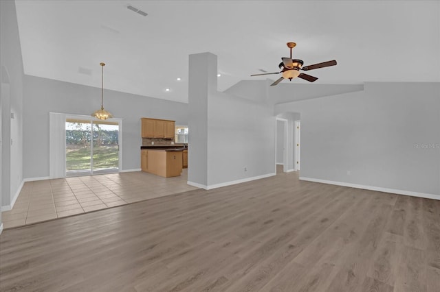 unfurnished living room with ceiling fan, light wood-type flooring, and vaulted ceiling