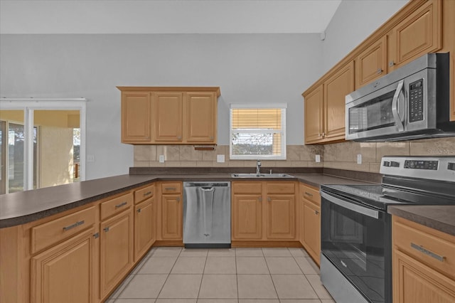 kitchen with sink, tasteful backsplash, kitchen peninsula, light tile patterned floors, and appliances with stainless steel finishes