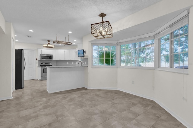 kitchen featuring appliances with stainless steel finishes, white cabinetry, hanging light fixtures, kitchen peninsula, and plenty of natural light