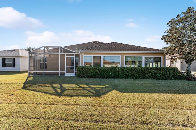 rear view of house with a lawn and glass enclosure