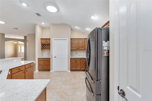 kitchen with stainless steel fridge, light tile patterned floors, and lofted ceiling