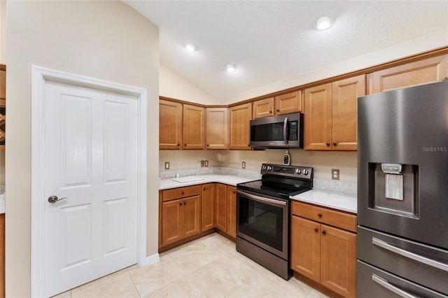 kitchen with light tile patterned flooring, lofted ceiling, and appliances with stainless steel finishes