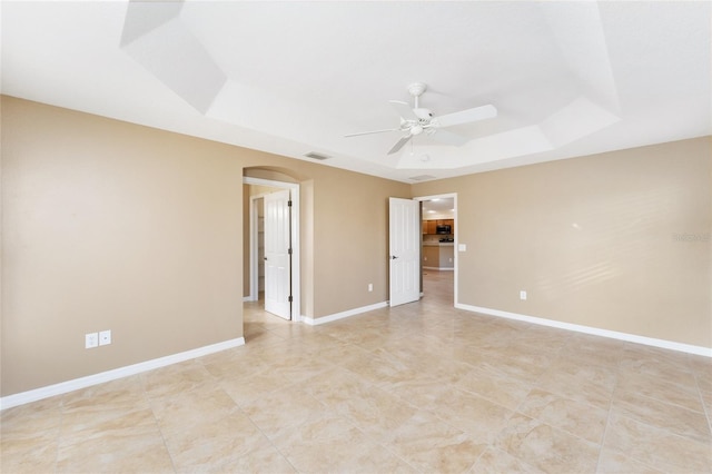 unfurnished room with ceiling fan and a tray ceiling