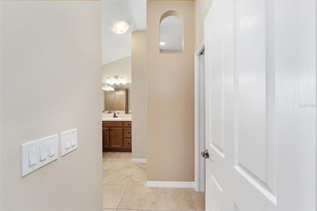 hallway featuring sink and light tile patterned flooring