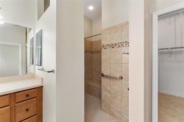 bathroom with tile patterned floors, vanity, and a tile shower