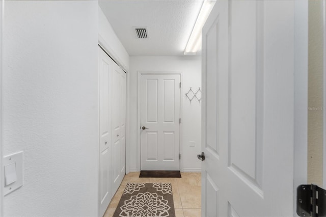 hall with light tile patterned floors and a textured ceiling