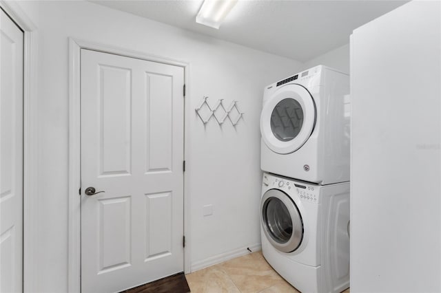 clothes washing area featuring stacked washer / drying machine and light tile patterned flooring