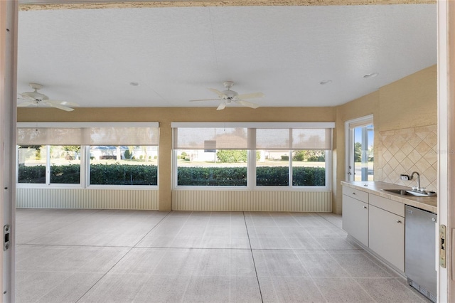 unfurnished sunroom featuring ceiling fan and sink