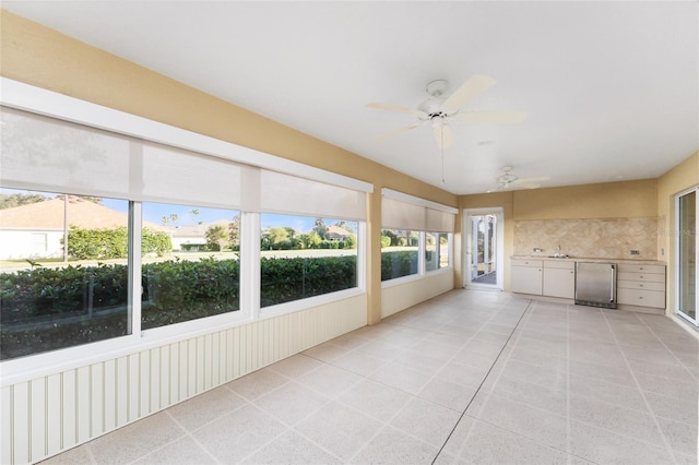 unfurnished sunroom featuring ceiling fan and sink