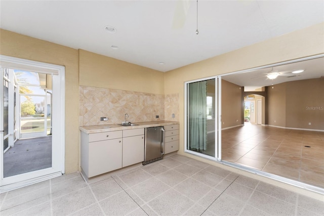 kitchen with decorative backsplash, refrigerator, a healthy amount of sunlight, and white cabinetry