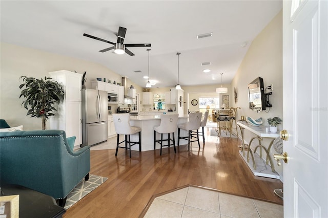 tiled living room featuring vaulted ceiling and ceiling fan