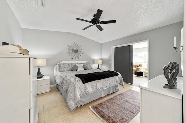 tiled bedroom featuring a textured ceiling, ceiling fan, and vaulted ceiling