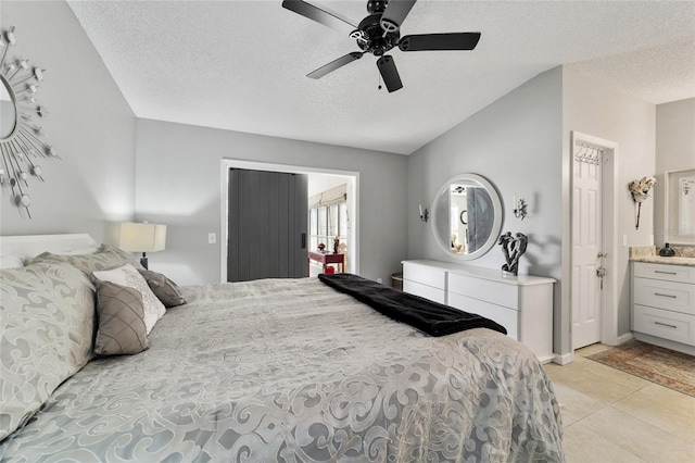 bedroom featuring ceiling fan, lofted ceiling, a textured ceiling, and connected bathroom