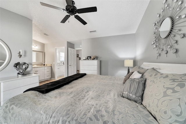 bedroom featuring a textured ceiling, ensuite bath, and ceiling fan