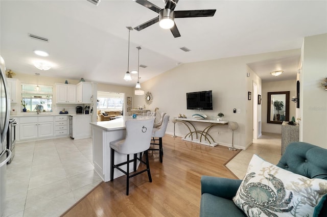 kitchen featuring a kitchen breakfast bar, backsplash, decorative light fixtures, white cabinets, and a center island