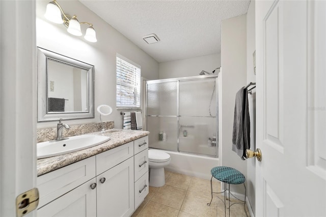 full bathroom featuring vanity, combined bath / shower with glass door, tile patterned flooring, toilet, and a textured ceiling