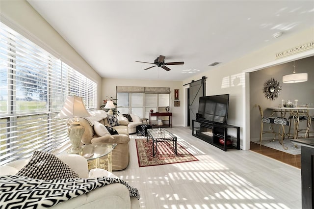 living room featuring a barn door and ceiling fan