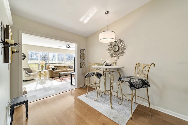 dining area featuring hardwood / wood-style floors, ceiling fan, and vaulted ceiling