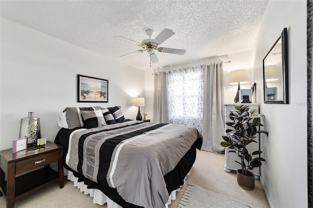 bedroom featuring light carpet, a textured ceiling, and ceiling fan