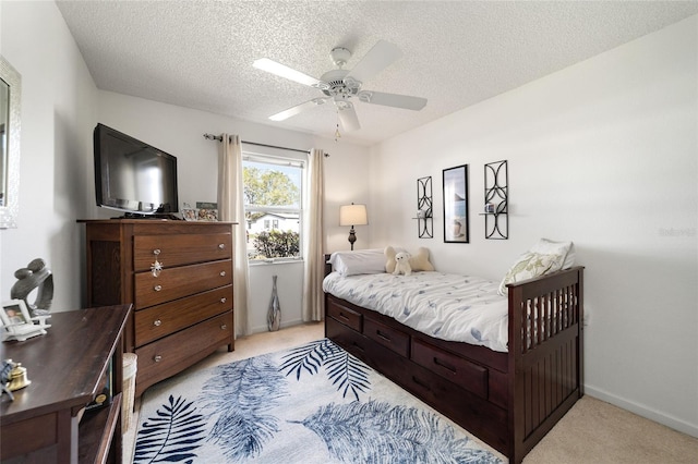 bedroom with ceiling fan, light colored carpet, and a textured ceiling