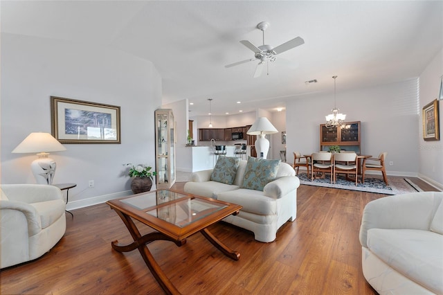 living room featuring ceiling fan with notable chandelier and dark hardwood / wood-style floors