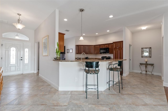 kitchen featuring a breakfast bar area, pendant lighting, kitchen peninsula, and light stone countertops