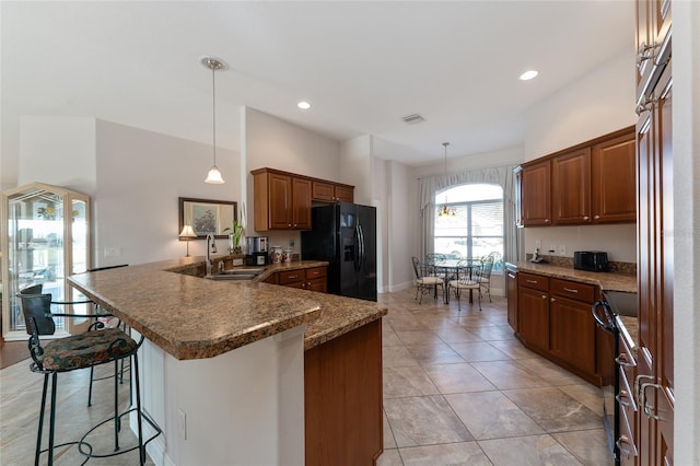 kitchen with a kitchen bar, kitchen peninsula, black fridge with ice dispenser, electric range oven, and pendant lighting