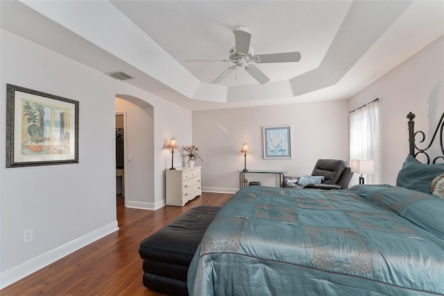 bedroom with ceiling fan, dark hardwood / wood-style flooring, and a raised ceiling