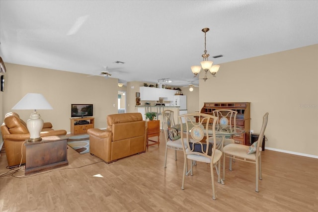 dining area featuring a textured ceiling, light hardwood / wood-style floors, and ceiling fan with notable chandelier