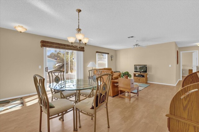 dining space with a textured ceiling, light hardwood / wood-style flooring, and ceiling fan with notable chandelier