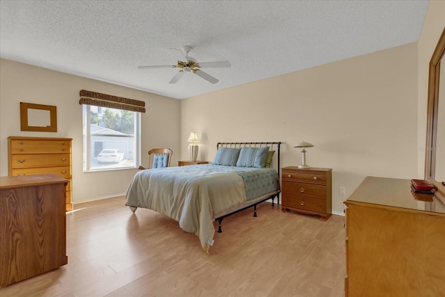 bedroom featuring ceiling fan, light hardwood / wood-style floors, and a textured ceiling