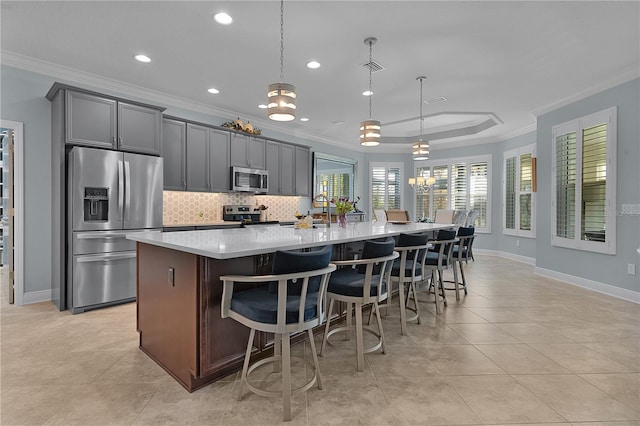 kitchen with decorative light fixtures, stainless steel appliances, a kitchen breakfast bar, a large island, and crown molding