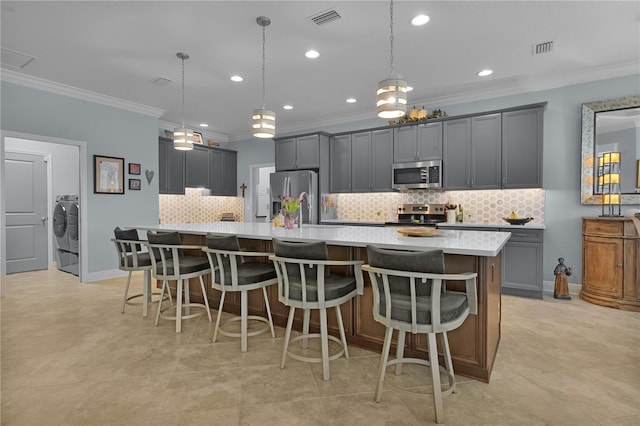 kitchen featuring decorative light fixtures, gray cabinets, stainless steel appliances, and separate washer and dryer