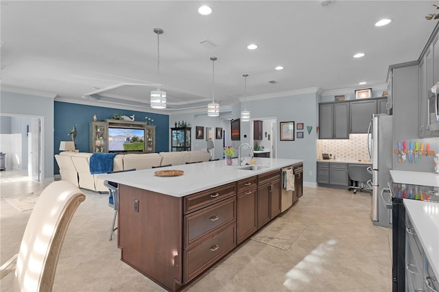 kitchen featuring decorative light fixtures, sink, backsplash, a kitchen breakfast bar, and a kitchen island with sink