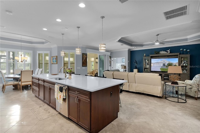 kitchen with ceiling fan with notable chandelier, sink, hanging light fixtures, and a tray ceiling