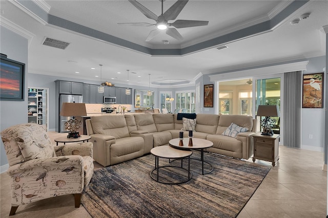 living room featuring light tile patterned floors, ornamental molding, a raised ceiling, and ceiling fan