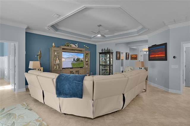 tiled living room with ceiling fan, ornamental molding, and a tray ceiling