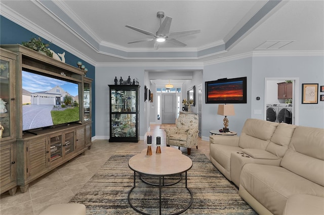 living room with ceiling fan, a tray ceiling, ornamental molding, and washer / dryer