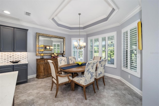 dining space featuring an inviting chandelier, crown molding, and a tray ceiling