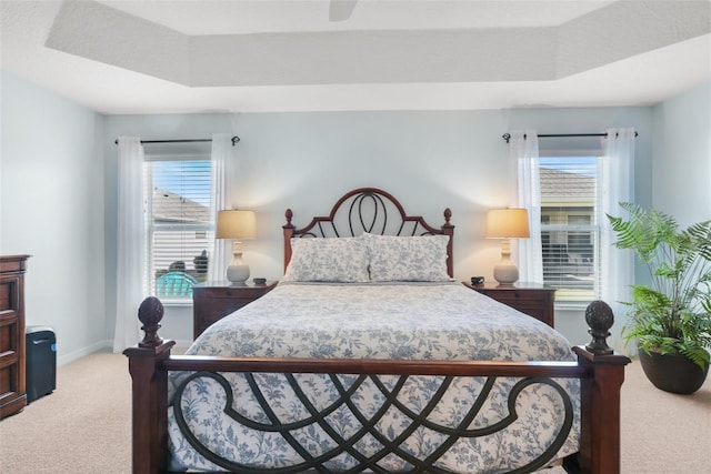 bedroom with a tray ceiling, ceiling fan, and carpet flooring