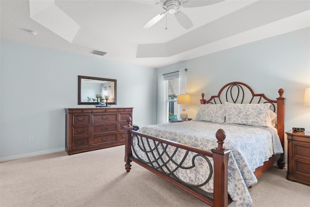 carpeted bedroom with a tray ceiling and ceiling fan