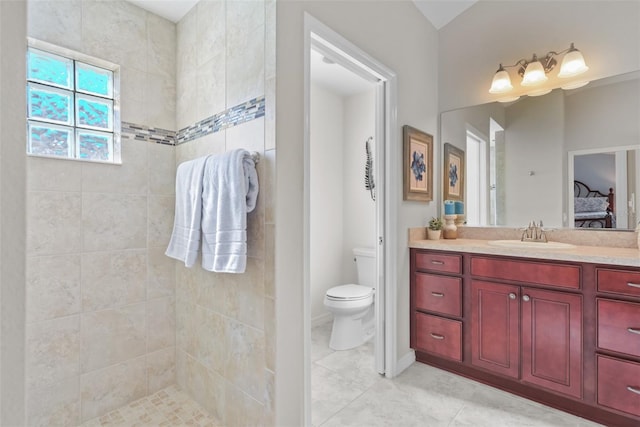 bathroom featuring a tile shower, tile patterned flooring, vanity, and toilet