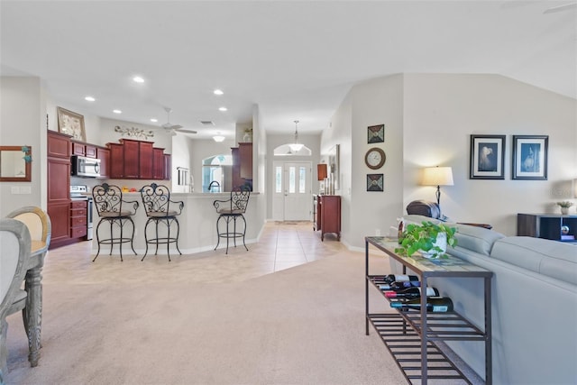 living room with ceiling fan, light carpet, and vaulted ceiling