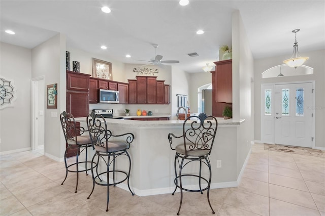 kitchen with kitchen peninsula, a kitchen breakfast bar, stainless steel appliances, ceiling fan, and pendant lighting