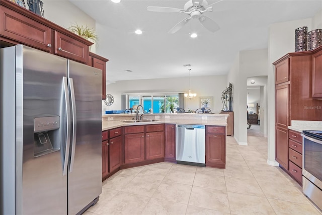 kitchen featuring pendant lighting, ceiling fan with notable chandelier, sink, kitchen peninsula, and stainless steel appliances