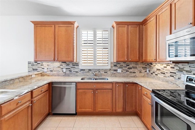 kitchen with backsplash, light stone counters, sink, and appliances with stainless steel finishes