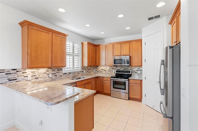 kitchen with tasteful backsplash, a kitchen breakfast bar, light stone counters, kitchen peninsula, and appliances with stainless steel finishes