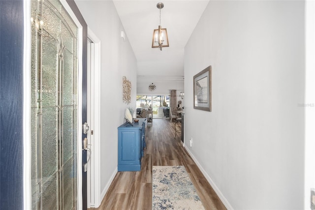 corridor with hardwood / wood-style floors and vaulted ceiling