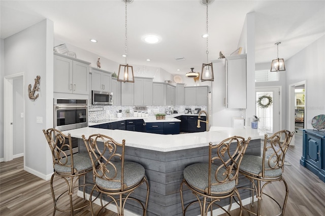 kitchen featuring hanging light fixtures, tasteful backsplash, a kitchen island, a breakfast bar area, and blue cabinets