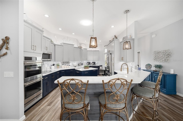 kitchen featuring stainless steel appliances, a breakfast bar, pendant lighting, decorative backsplash, and blue cabinets